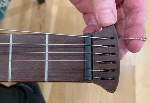 Insert ball end of string through in headstock