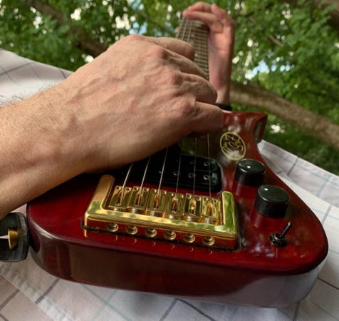 Action shot of Gold Compact Bridge in Red Trouper travel Guitar